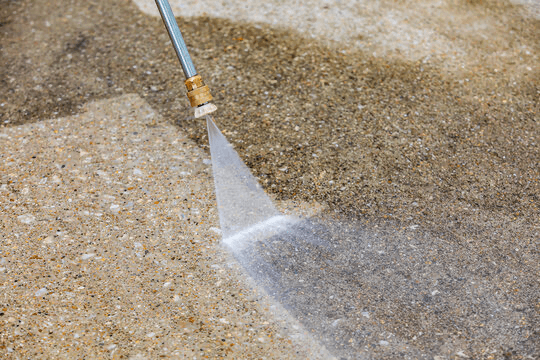 Pressure washer wand blasting clean a concrete driveway
