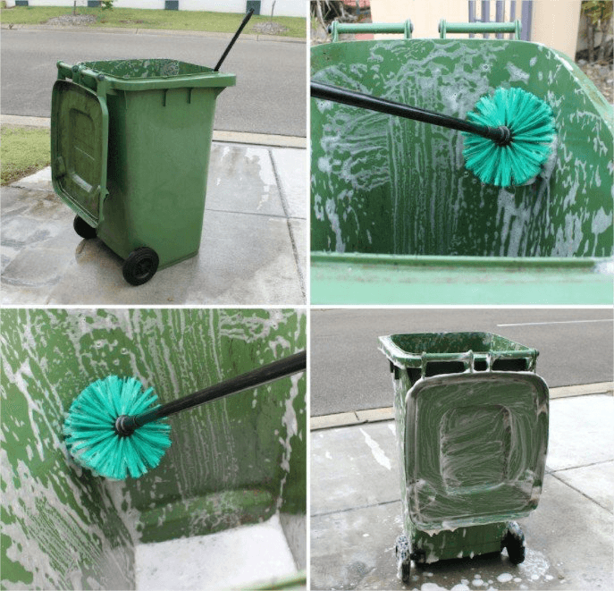 Green garbage bin being scrubbed clean with foamy soap