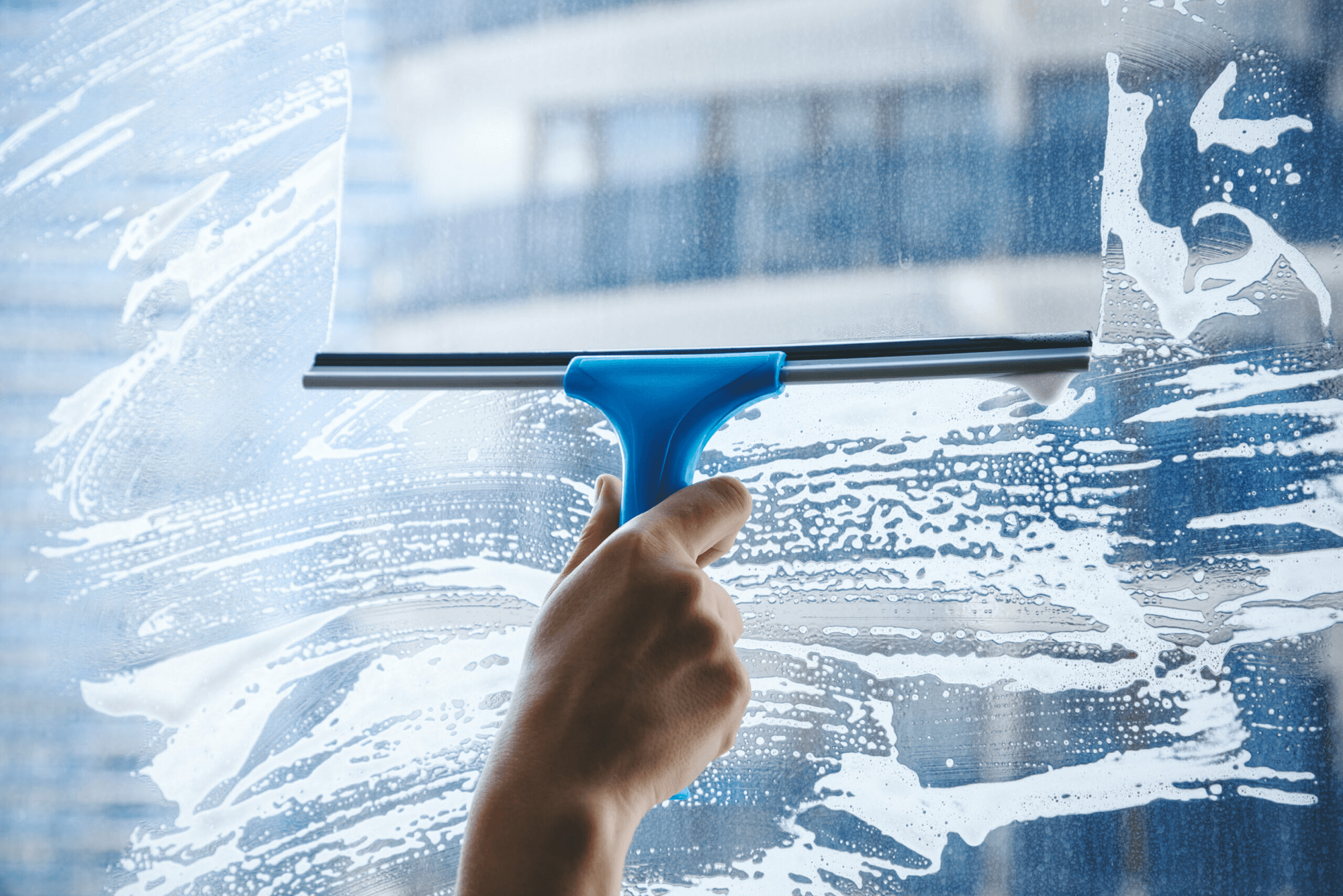 Squeegee cleaning a soapy window to a streak-free shine